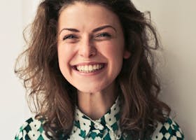 Portrait of a joyful brunette woman with a vibrant smile indoors, capturing happiness and positivity.